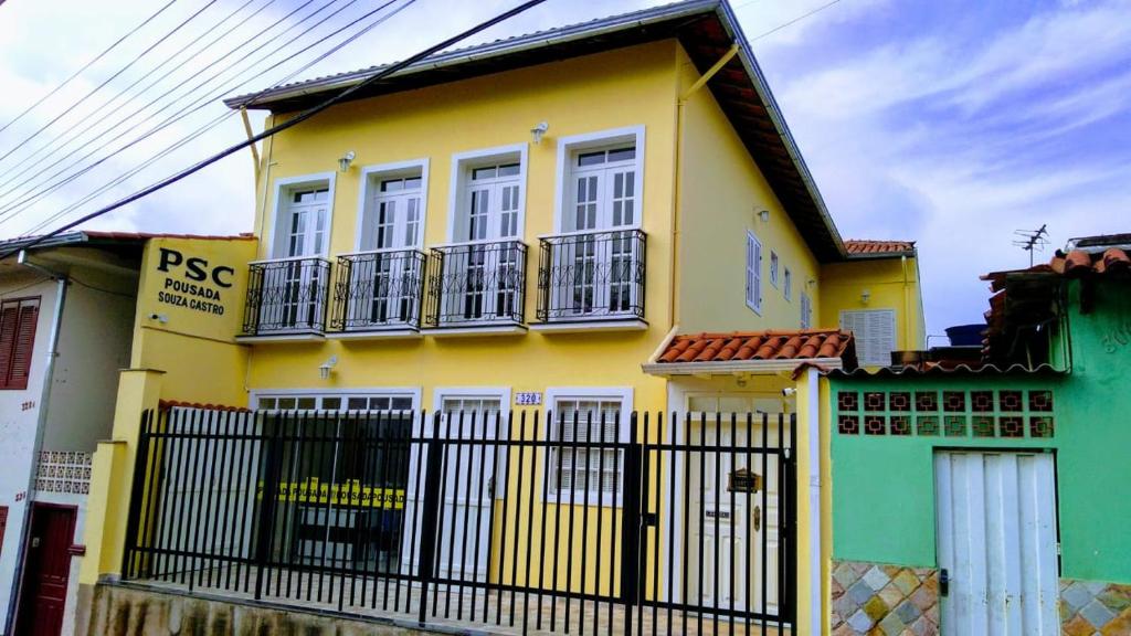 欧鲁普雷图Pousada Souza Castro的黄色和绿色的房子,有黑色的围栏