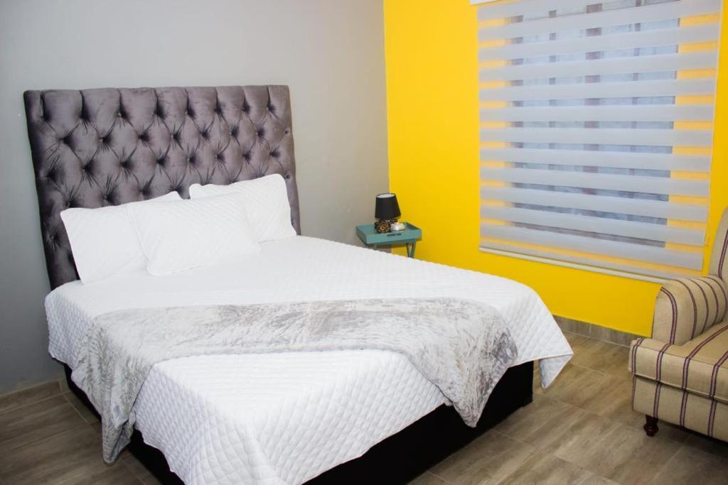 索韦托Rukza's Guest House的一间卧室设有一张床和黄色的墙壁