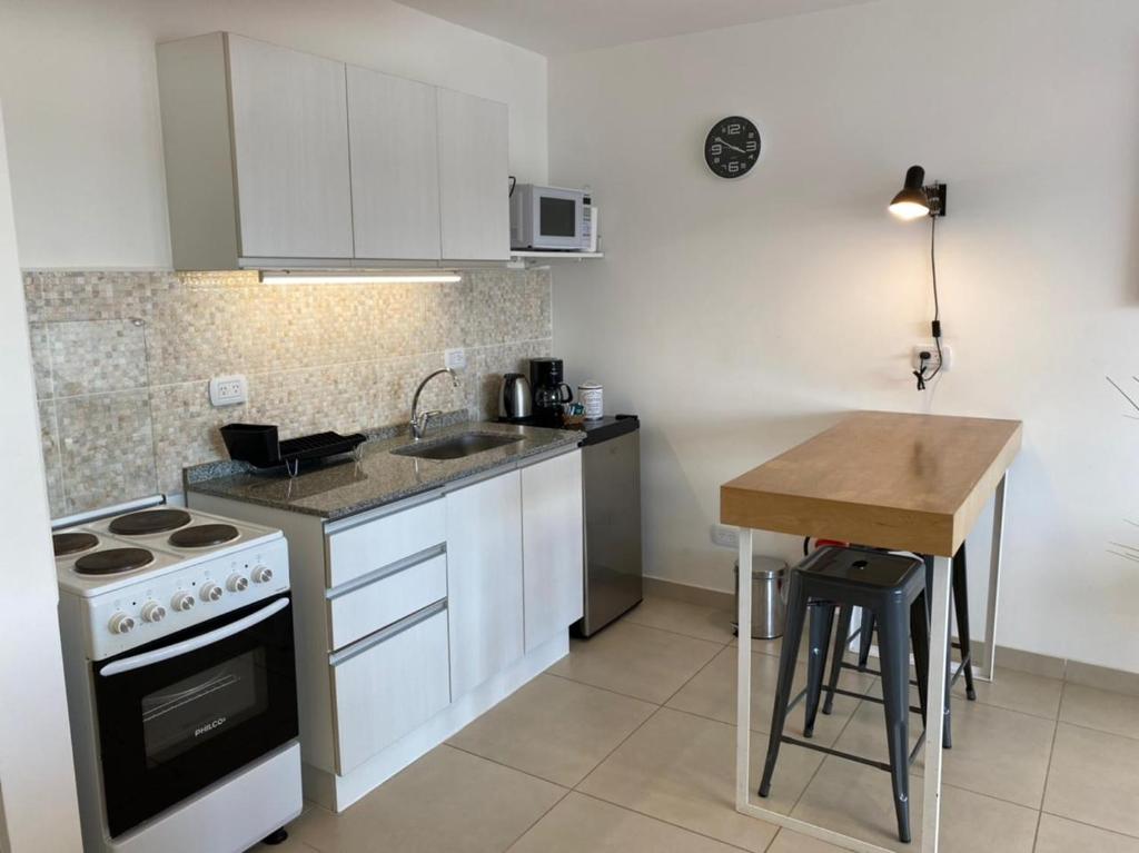 乌斯怀亚Penguins Flats 3的厨房配有白色橱柜、炉灶和桌子。