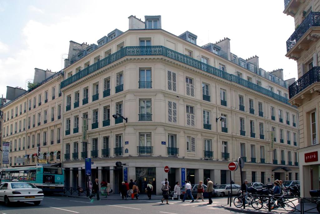 巴黎HOTEL DU PRINTEMPS的一座白色的大建筑,前面的人在步行