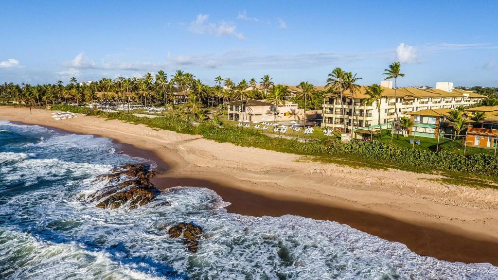萨尔瓦多卡图萨巴套房度假酒店的享有棕榈树和建筑海滩的空中景致