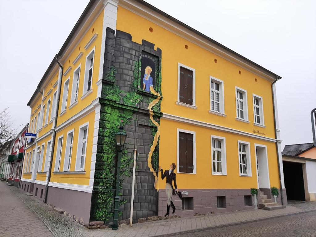 施韦特Ferienwohnung Zum Rapunzelturm的黄色的建筑,在建筑的一侧画着画