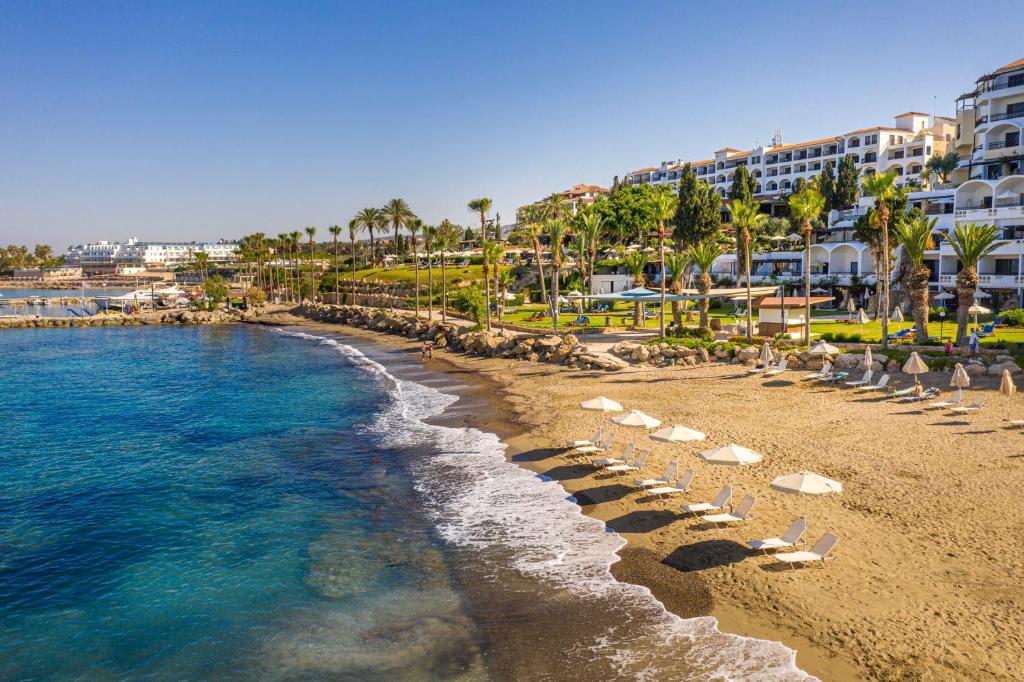 珊瑚湾塞浦路斯珊瑚海滩酒店和度假胜地的一个带躺椅的海滩和一个度假胜地
