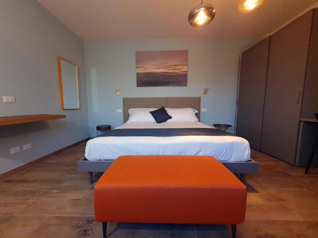 西尔米奥奈La Lampara的一间卧室配有一张床和一个橙色的搁脚凳