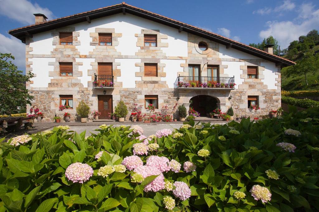 Anzuola伊瓦雷农舍酒店的一座大石头建筑,前面有鲜花