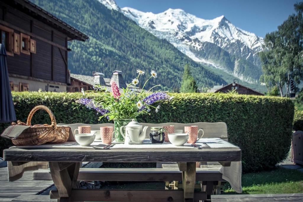 夏蒙尼-勃朗峰Paccard Locations Chamonix的一张野餐桌,上面有鲜花,还有山
