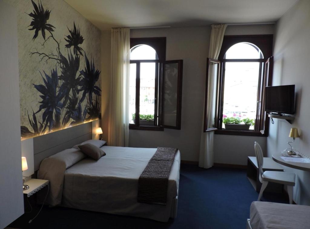 马尼亚戈Albergo Leon D'Oro的酒店客房设有一张床和两个窗户。