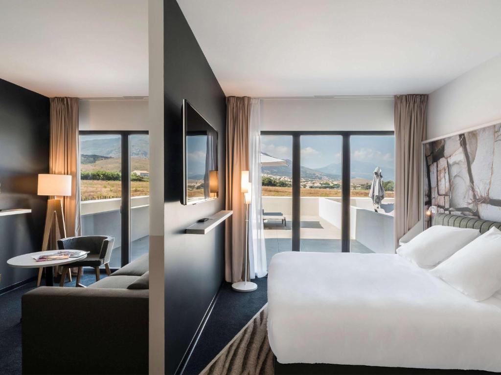 比居格利亚Mercure Hotel & Spa Bastia Biguglia的酒店客房配有白色的床和沙发。