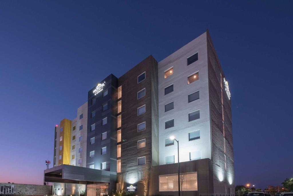 瓜达拉哈拉Microtel Inn & Suites by Wyndham Guadalajara Sur的一座高大的白色建筑,有很多窗户