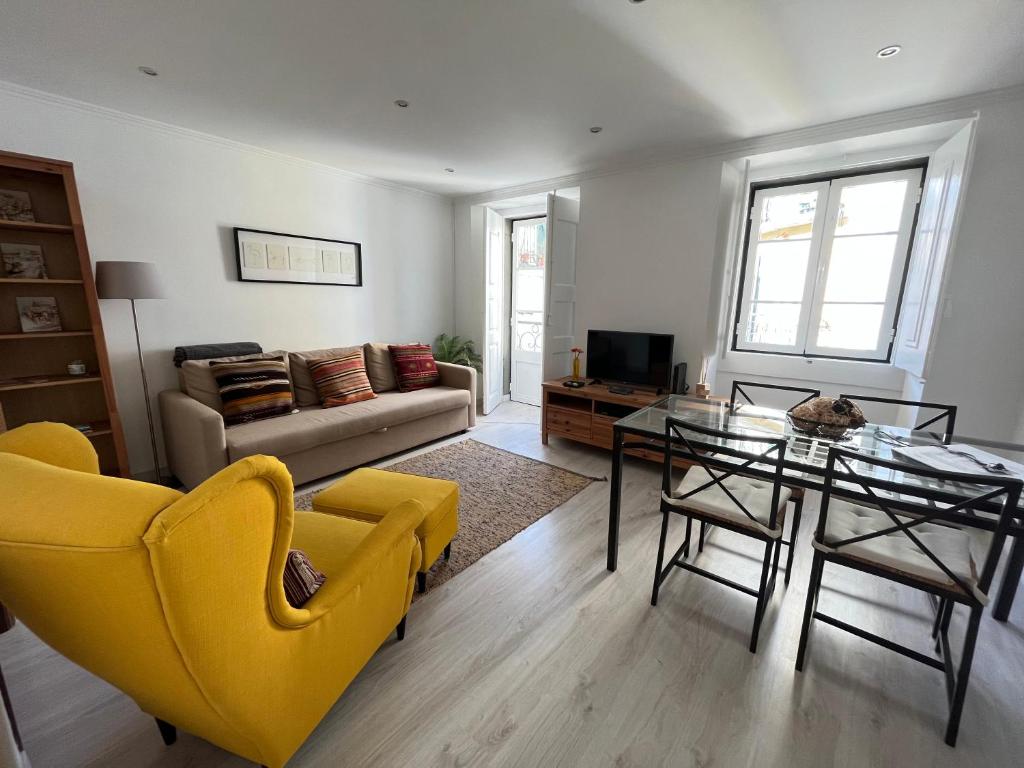 里斯本Travessa do Pasteleiro Apartment by Trip2Portugal的客厅配有玻璃桌和黄色椅子