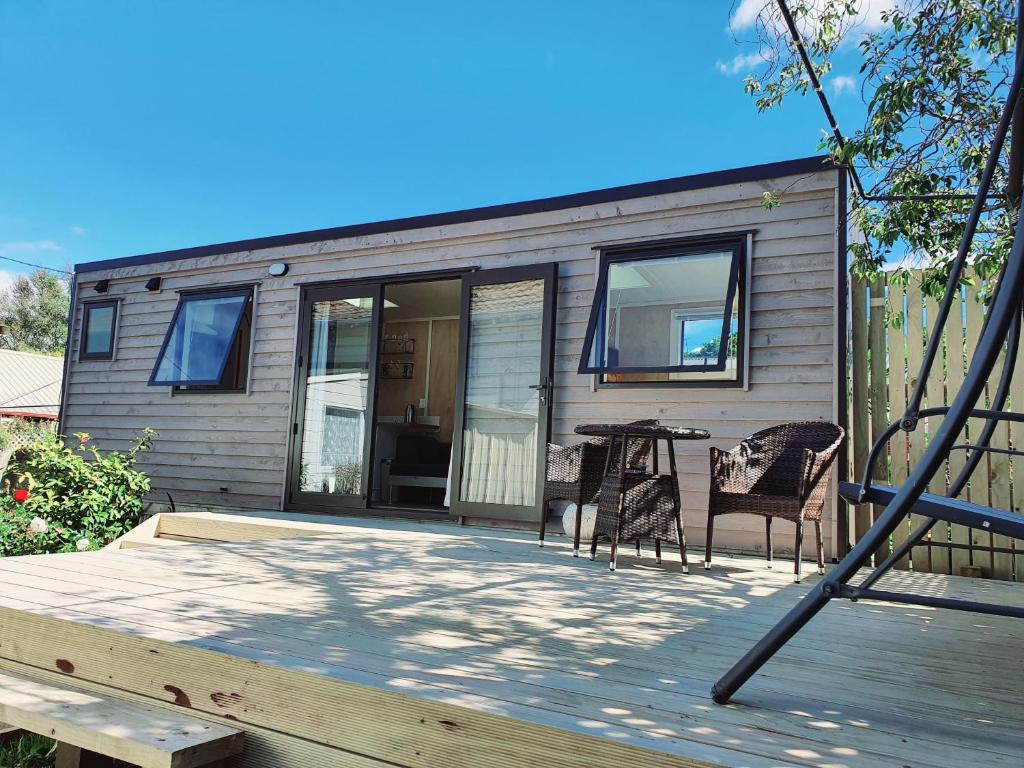 但尼丁Dunedin Luxurious Retreat Cabin的一座小房子,甲板上摆放着桌椅