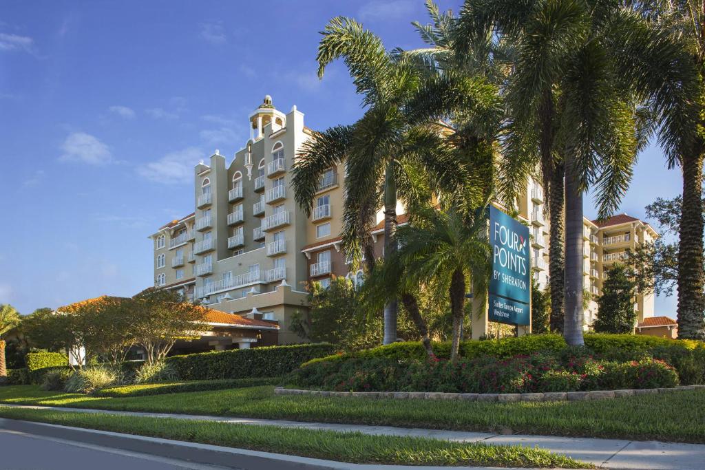 坦帕坦帕机场西岸福朋喜来登酒店的一座楼前有棕榈树的酒店