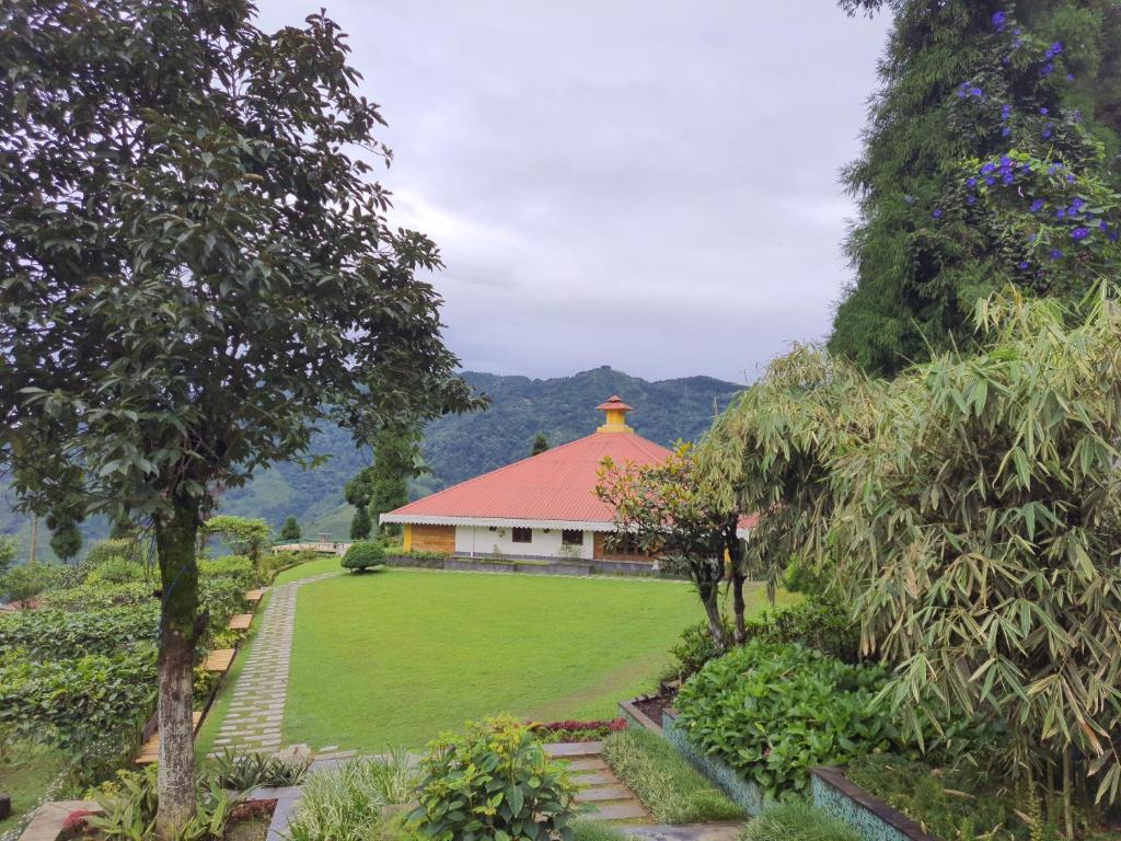 大吉岭Chamong Chiabari Mountain Retreat的花园中一座红色屋顶的建筑