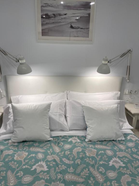 马拉加Nuestro Rinconcito del Soho的一张带白色枕头的床和一张墙上的照片