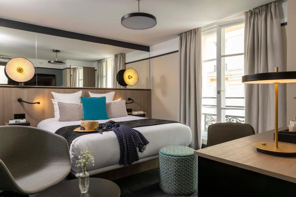 巴黎Hôtel Opéra Liège的酒店客房配有一张床铺、一张桌子和一张书桌。