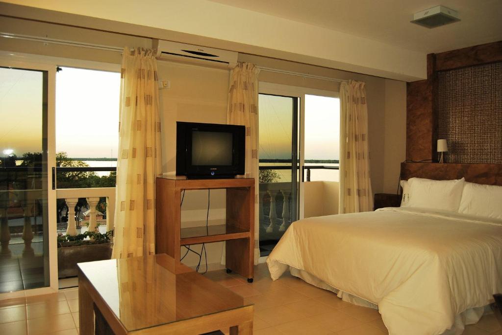 科连特斯拉罗扎达套房酒店的一间卧室配有一张床、一台电视和一个阳台