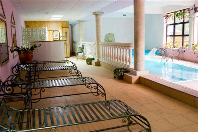 科尔别卢夫Hotel Fero Lux的一个带长椅的酒店客房内的大型游泳池