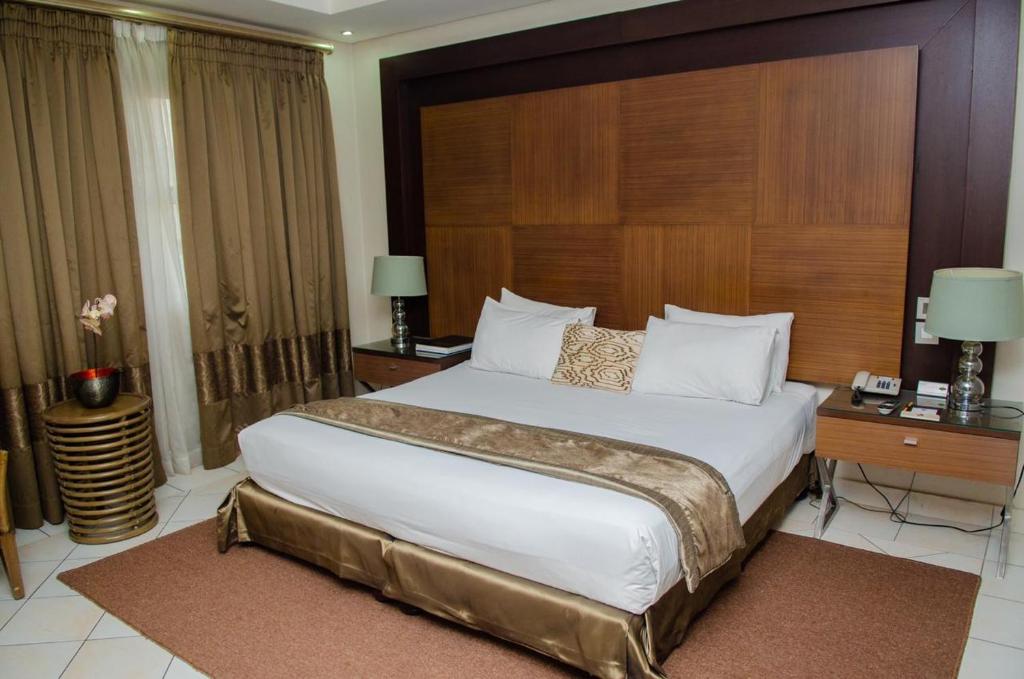 马普托2001酒店的一间卧室配有一张大床和木制床头板