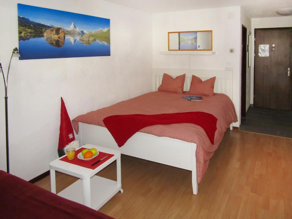 采尔马特Apartment Sungold-1 by Interhome的一间卧室配有一张床和一张桌子及一碗水果