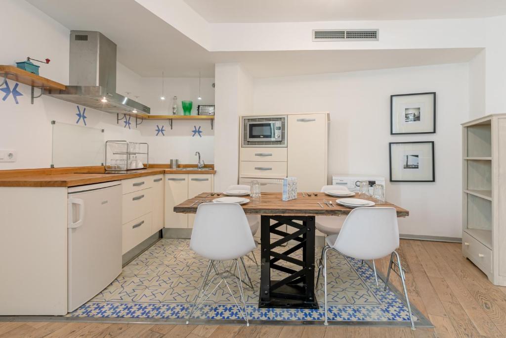 塞维利亚Hércules XCI Apartments的厨房配有木桌和白色橱柜。