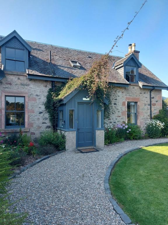 因弗内斯The Cottage, The Loch Ness Cottage Collection的砂石车道上一扇蓝色门的房子