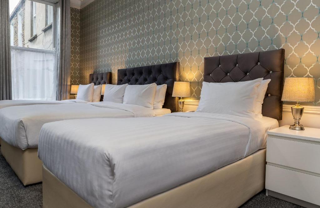 都柏林Clifden House by Nina的配有白色枕头的酒店客房内的两张床