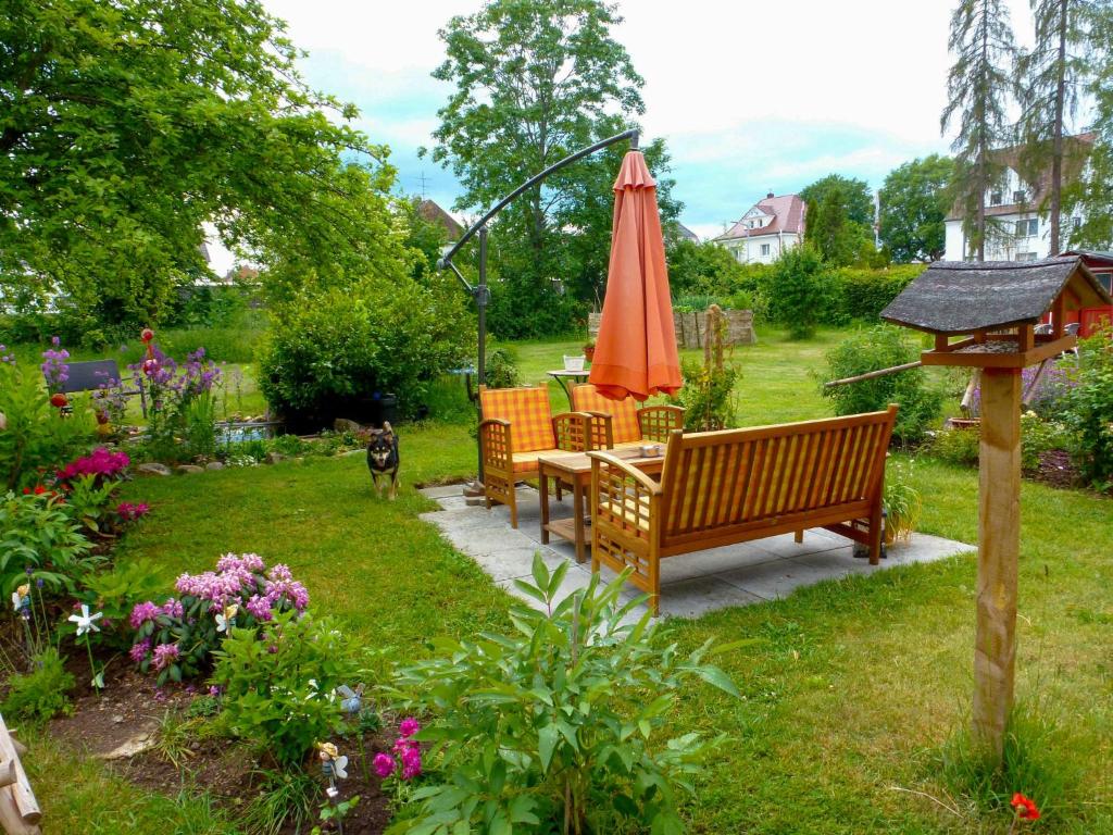 胡芬根Holiday Home Schmetterlingsgarten by Interhome的花园设有桌子、雨伞和狗