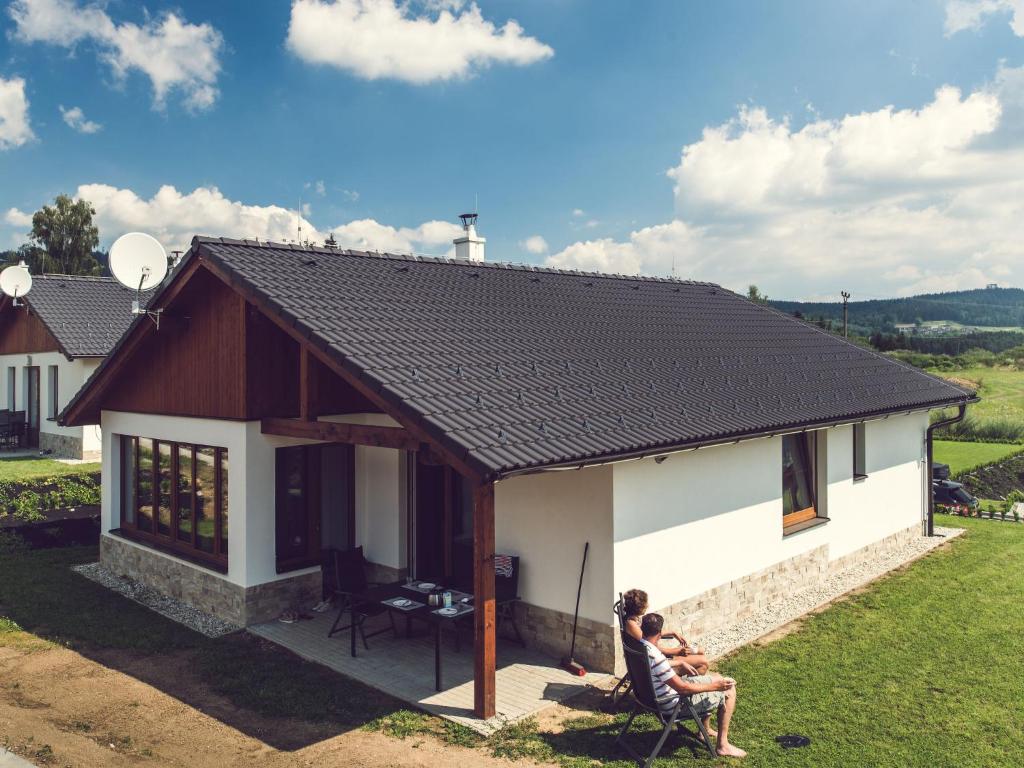 伏尔塔瓦河畔利普诺Holiday Home Residence Lipno by Interhome的两人坐在一个小房子外面