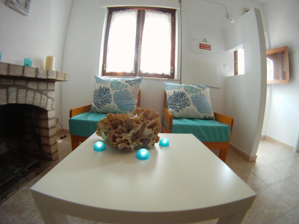 科武港Ahoy Porto Covo Hostel的客厅配有白色桌子和壁炉