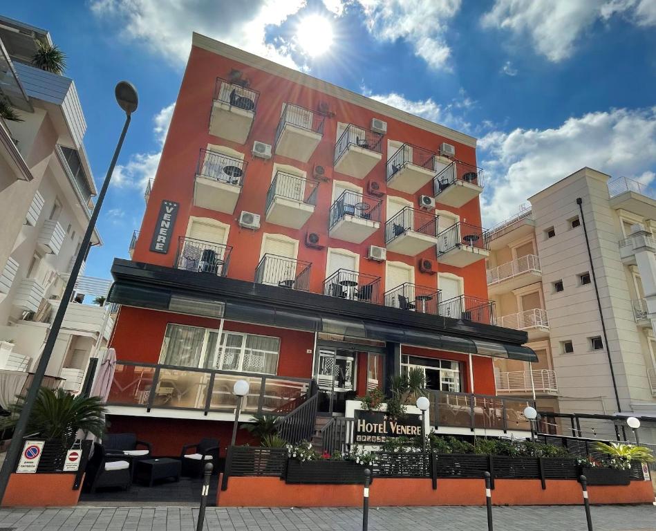 里米尼维奈蕾酒店的一座橙色的建筑,与两栋建筑旁边的酒店