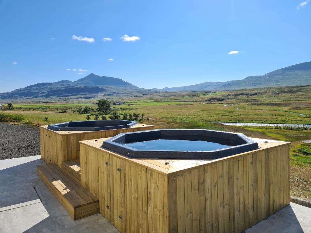 瓦玛里德Hlín Guesthouse的两个热水浴缸位于一个木制甲板上,享有山脉背景