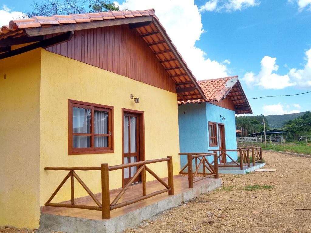 卡皮托利乌Chalé Águas Claras的黄色和蓝色的小房子,设有木门廊