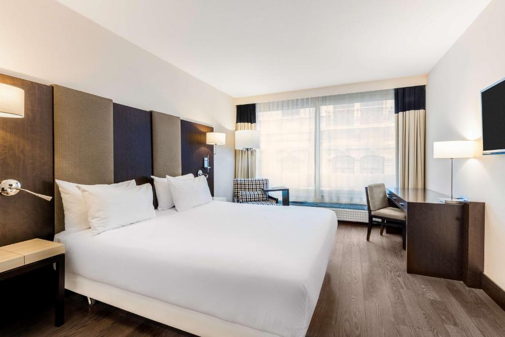 布鲁塞尔斯蒂芬妮NH酒店的酒店客房设有一张白色大床和一张书桌