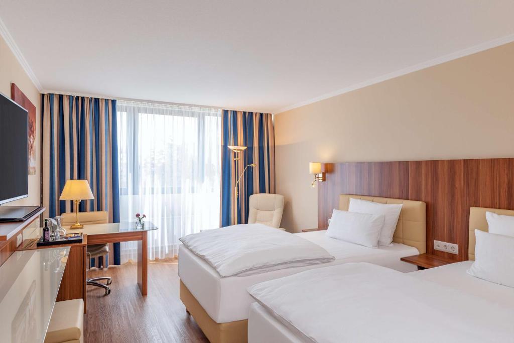 因戈尔施塔特NH因戈尔施塔特酒店的酒店客房设有两张床、一张桌子和一台电视。