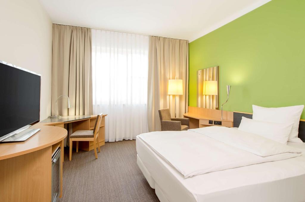 慕尼黑慕尼黑展览中心NH酒店的酒店客房配有一张床、一张书桌和一台电视。