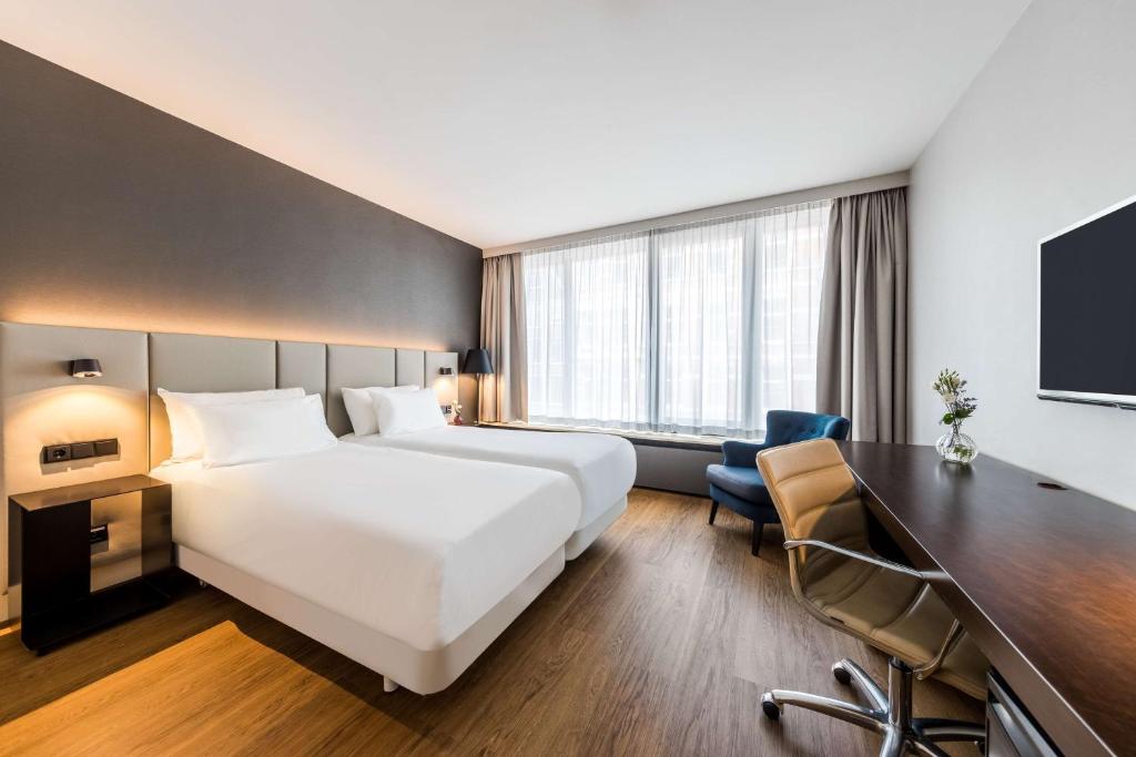 阿姆斯特丹阿姆斯特丹卡兰萨NH酒店的酒店客房设有一张白色大床和一张书桌