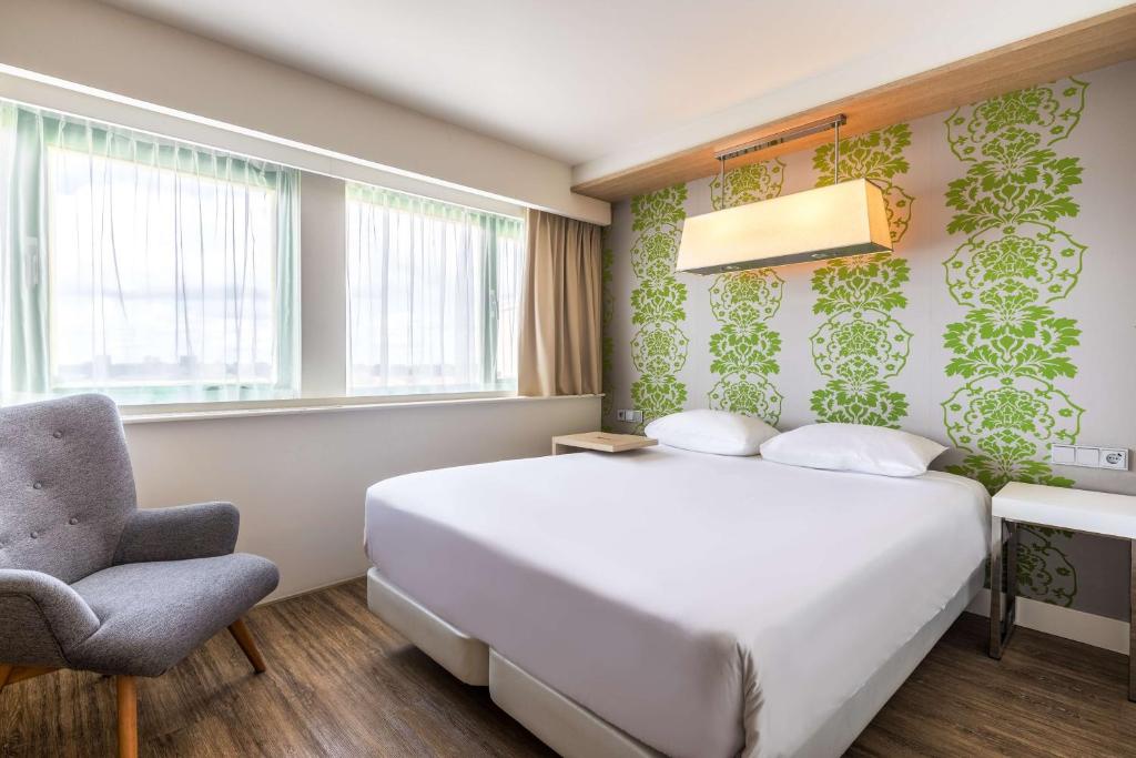 阿姆斯特丹阿姆斯特丹北NH酒店的卧室配有白色的床和椅子