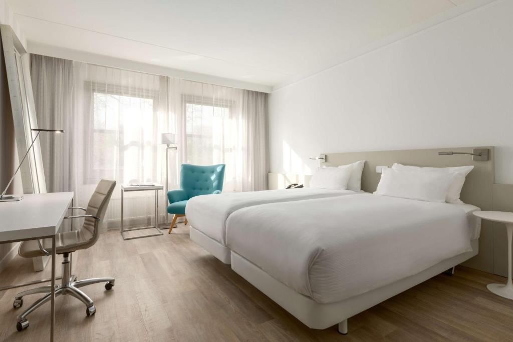 布森NH布森月塔巴克酒店的卧室配有一张白色大床、一张桌子和椅子