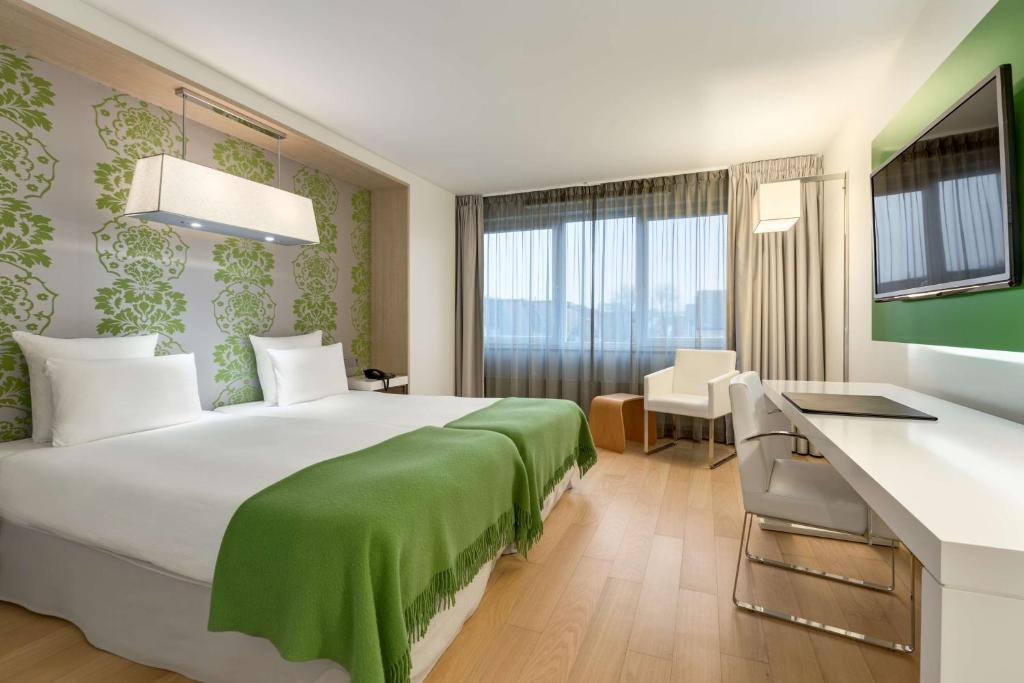 格罗宁根格罗宁根NH酒店的酒店客房设有一张大床和一张书桌。
