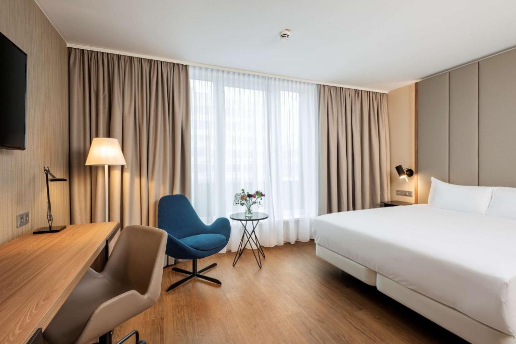 汉诺威NH Hannover的酒店客房配有一张床、一张桌子和一把椅子。