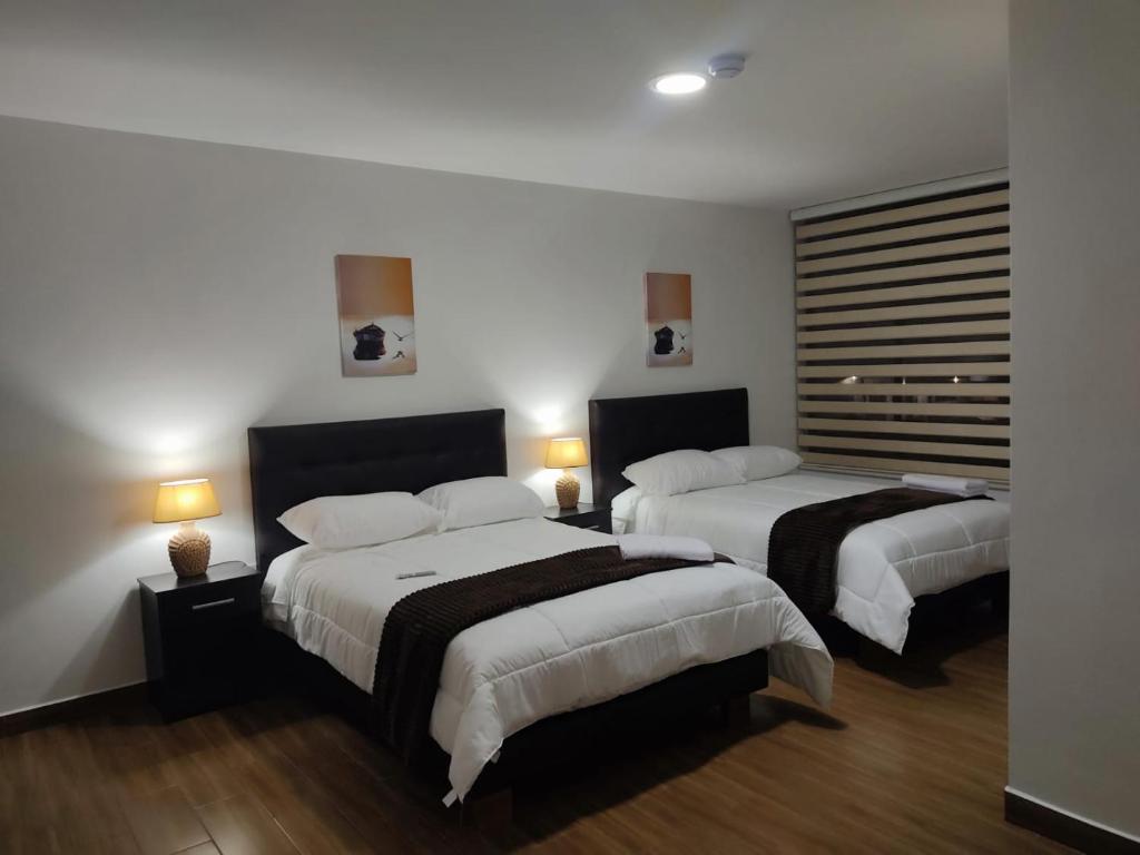 基多Hospedaje El Girasol TABABELA的酒店客房设有两张床和两盏灯。