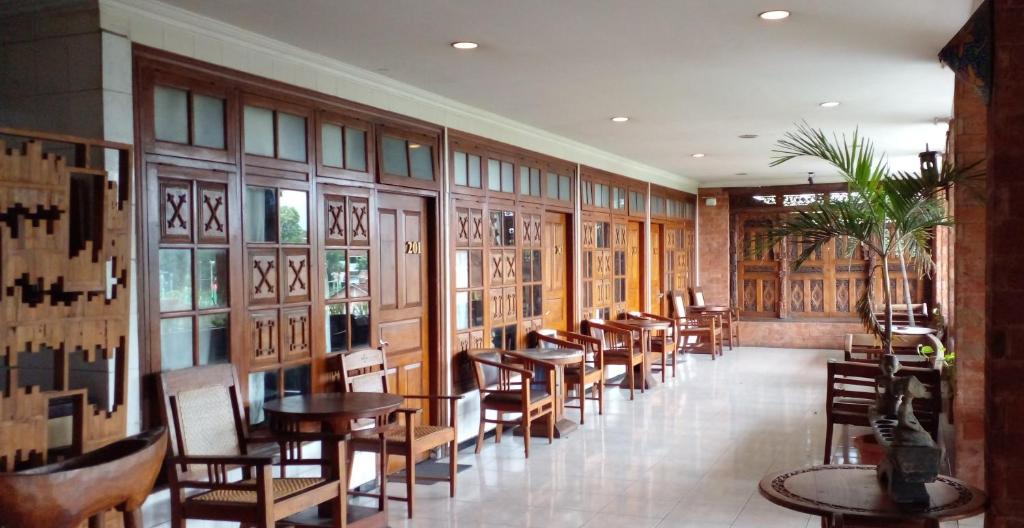 日惹Hotel Bifa Yogyakarta的餐厅设有木桌、椅子和窗户。