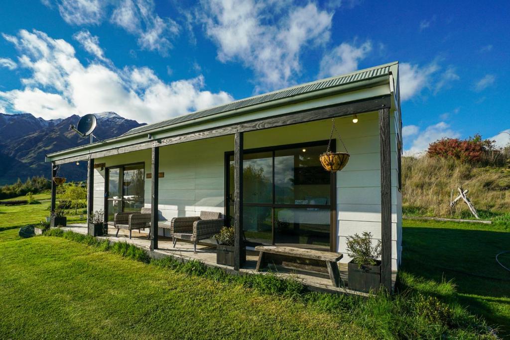 GlendhuGlendhu Station Cottage - Glendhu Bay Holiday Home的玻璃门和田野长凳的房子