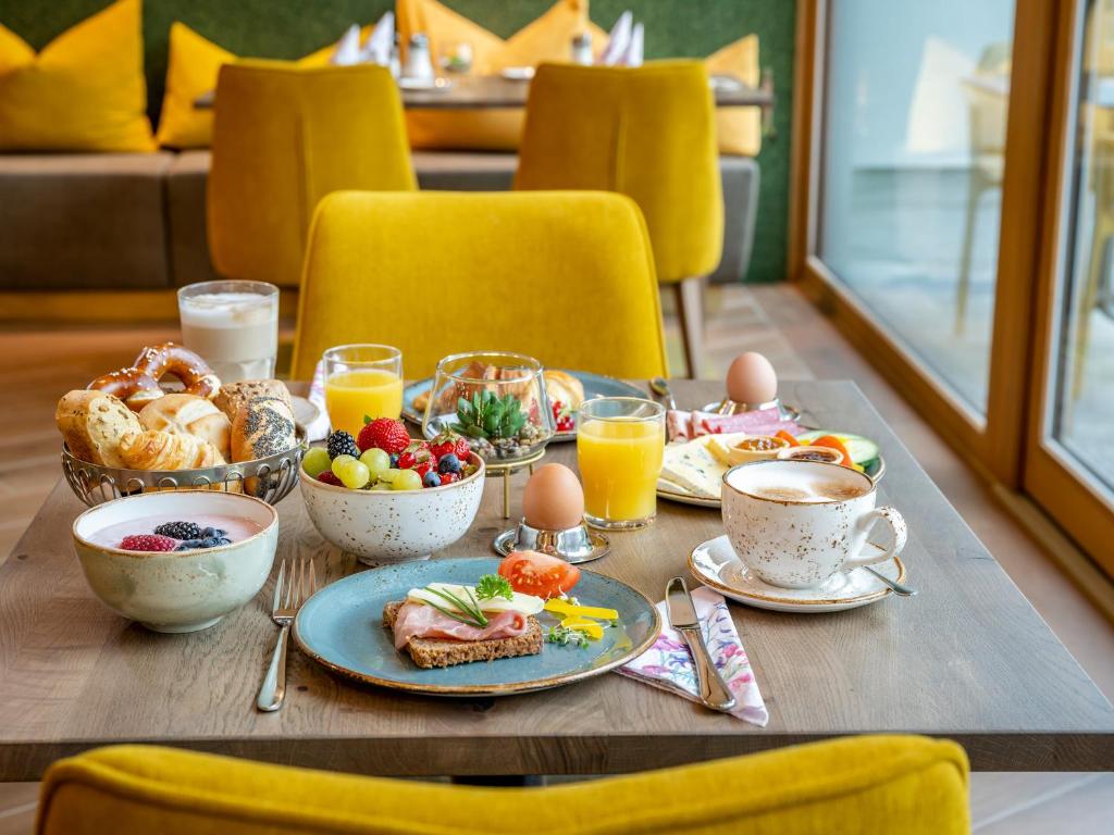 巴特法兴格Hotel FrechDachs的一张桌子,上面有早餐食品和橙汁