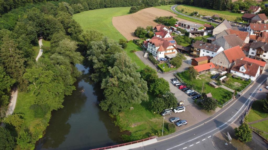 GräfendorfHotel Saaletalstuben的享有村庄和河流的空中景色