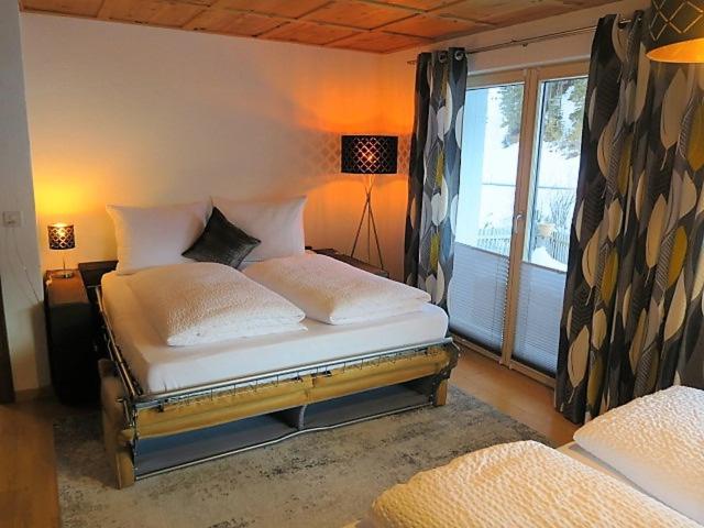 萨姆瑙恩Chasa Max的卧室配有带白色枕头的床和窗户。