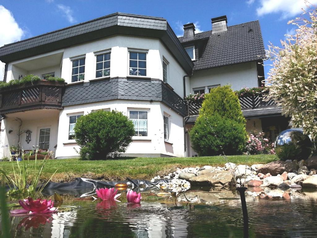 温特贝格录格 - 温特贝格宾馆的一座房子,前面有一个池塘,上面有粉红色的花