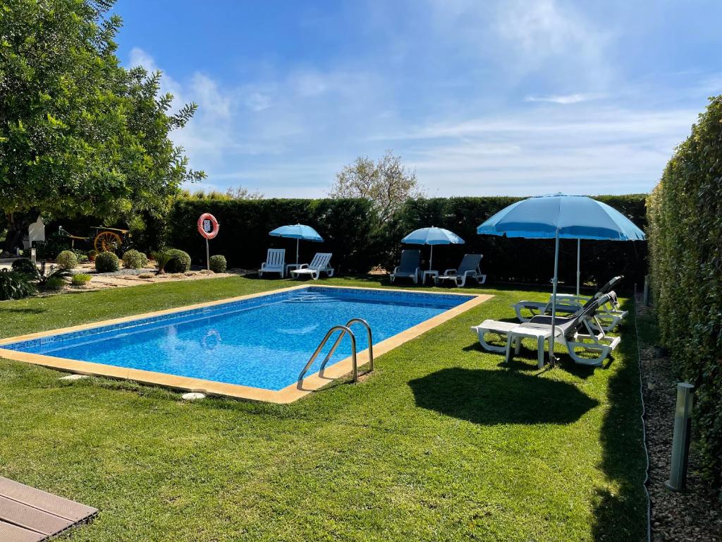 西尔韦斯Quinta dos Sapos的一个带遮阳伞的庭院内的游泳池