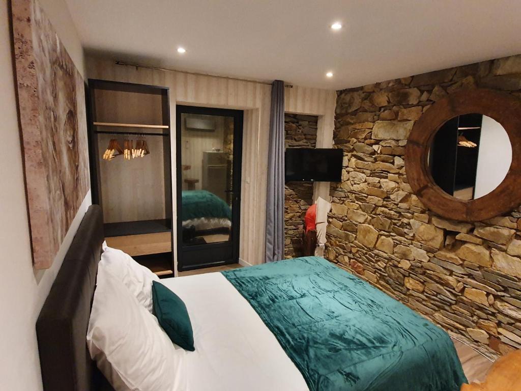拉尼翁Appartements C'Home un charme的卧室配有一张石墙内的大床
