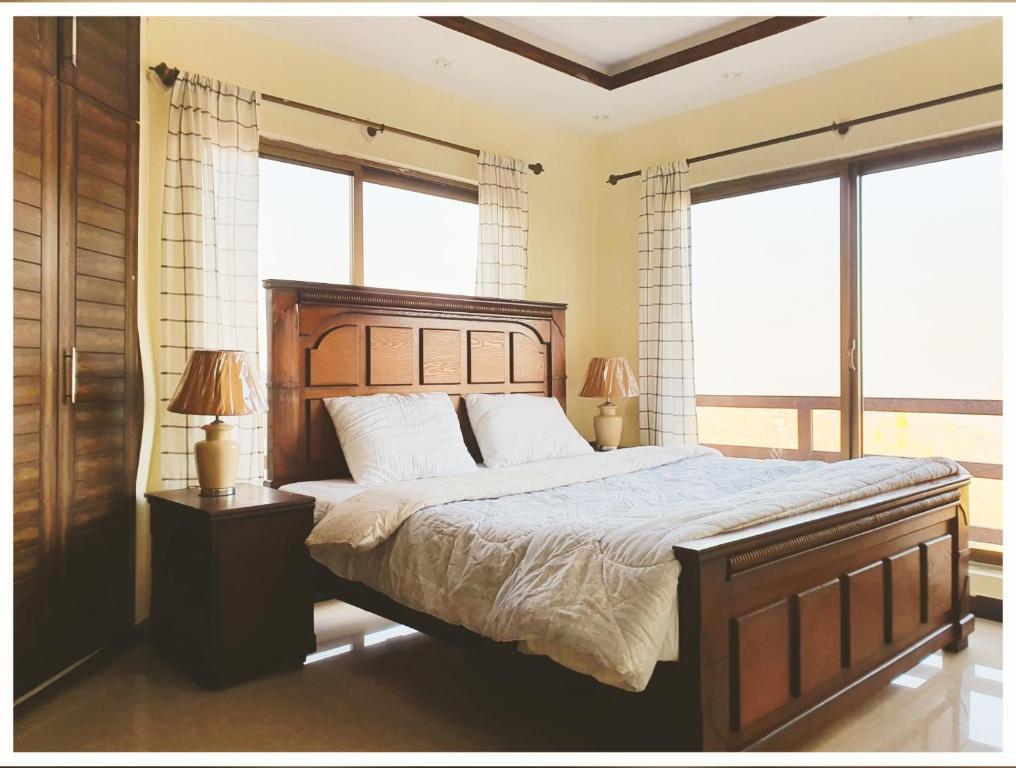 AusiaFull Serviced Cottage in Bhurban的一间卧室设有一张大床和两个窗户。